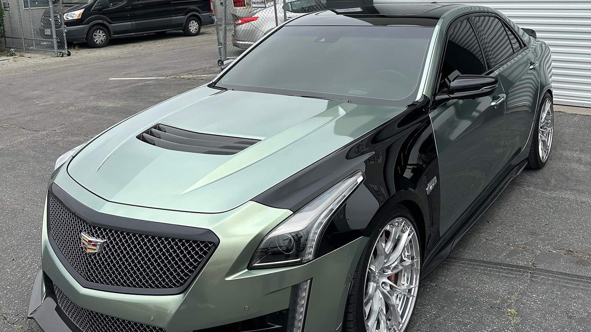 Cadillac CTS-V in two-tone sage green and gloss black, the split running hard down the fender and door with the hood, nose and front fenders green and the roof, rear doors and quarters black